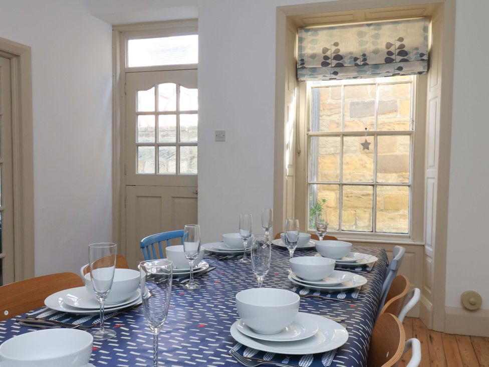 A dining room with a table set for meals at Beachside Cottage in Sandsend