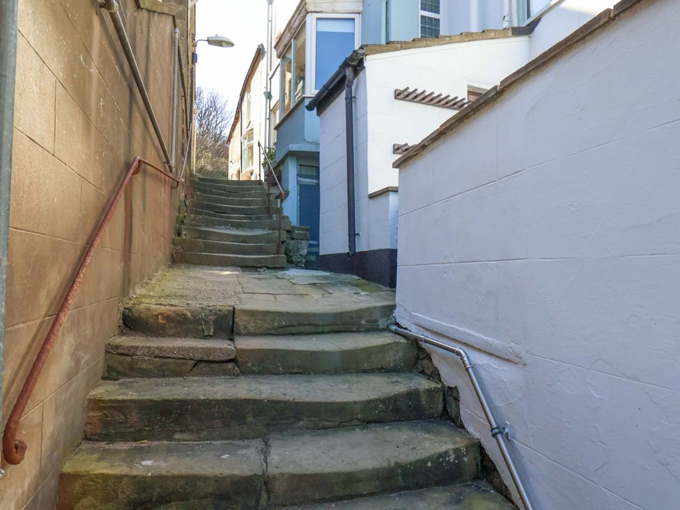 A stone staircase with a handrail and buildings on either side at Beachside Cottage in Sandsend