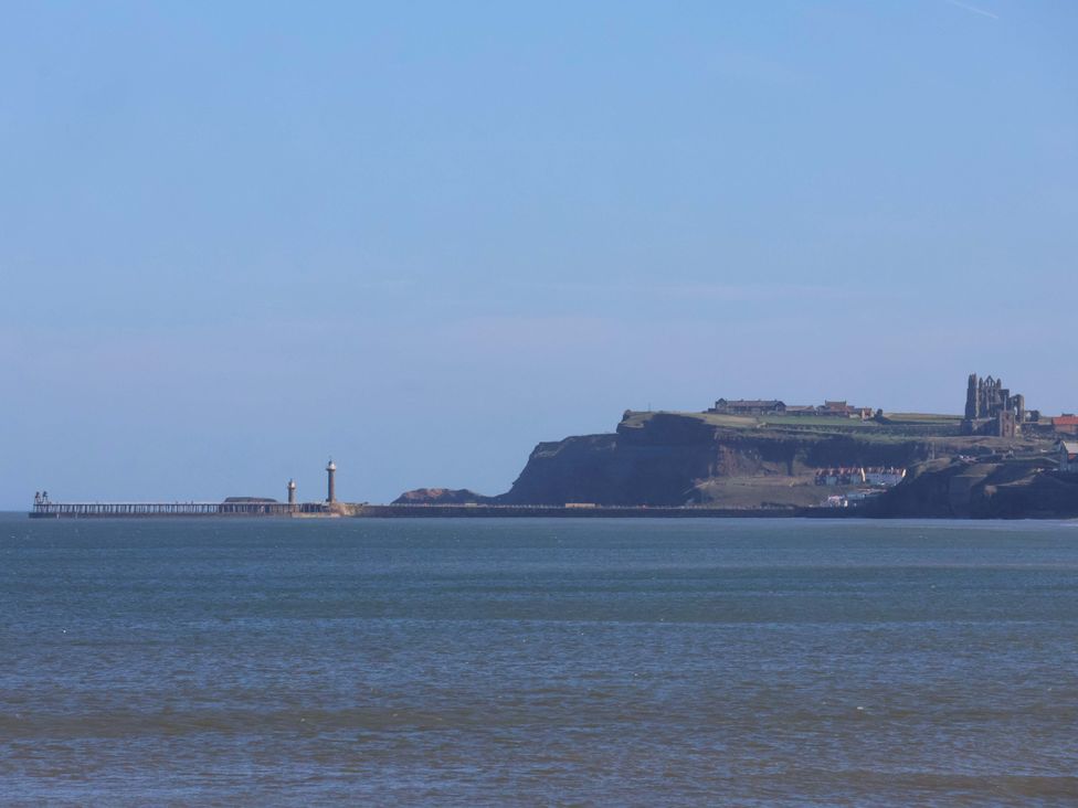 A view of a lighthouse and pier along the ocean at Beachside Cottage Sandsend