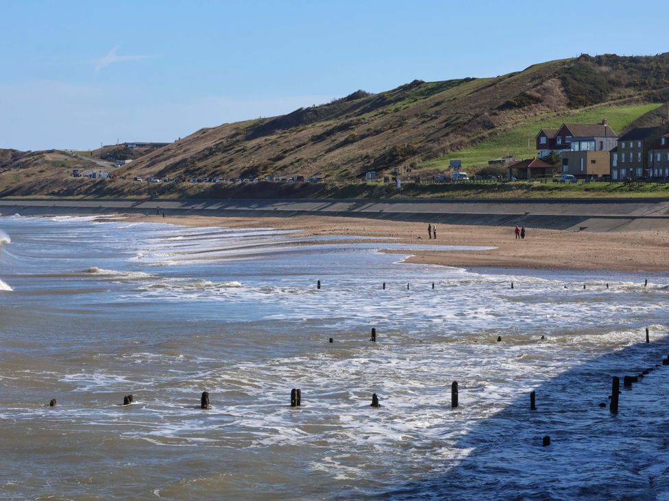 A beach with water and cliffs at Beachside Cottage in Sandsend