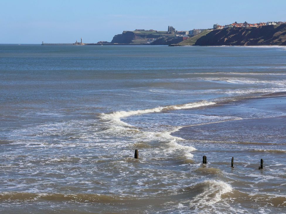 A coastal view with waves and a pier at Beachside Cottage Sandsend