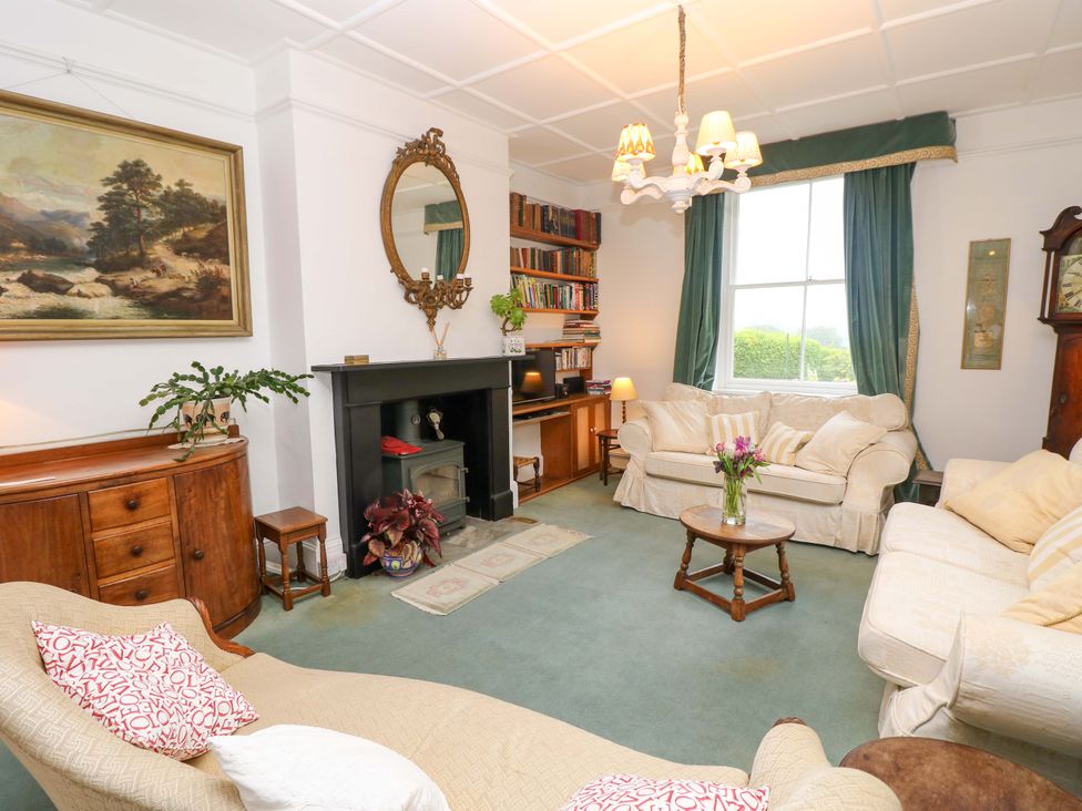 A living room with a sofa, table, and bookshelf at Woodlands in Freshwater