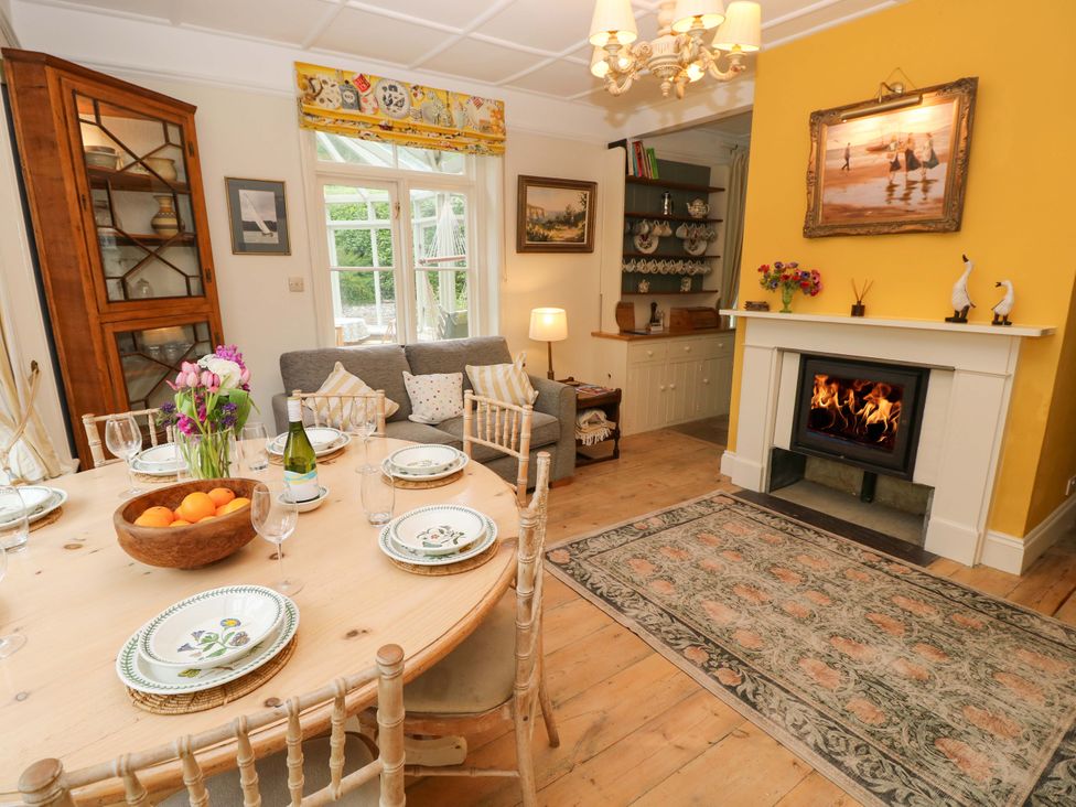 A dining room with a table and fireplace at Woodlands in Freshwater
