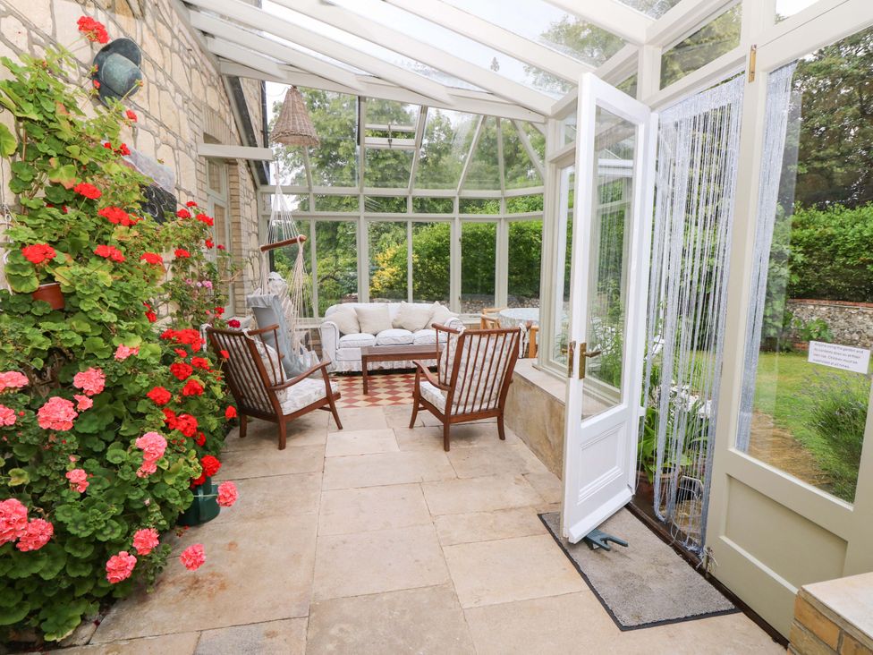 A conservatory with chairs and a sofa at Woodlands in Freshwater
