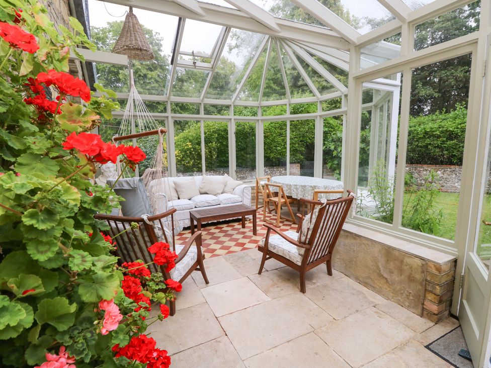 A conservatory with a sofa and dining table at Woodlands in Freshwater