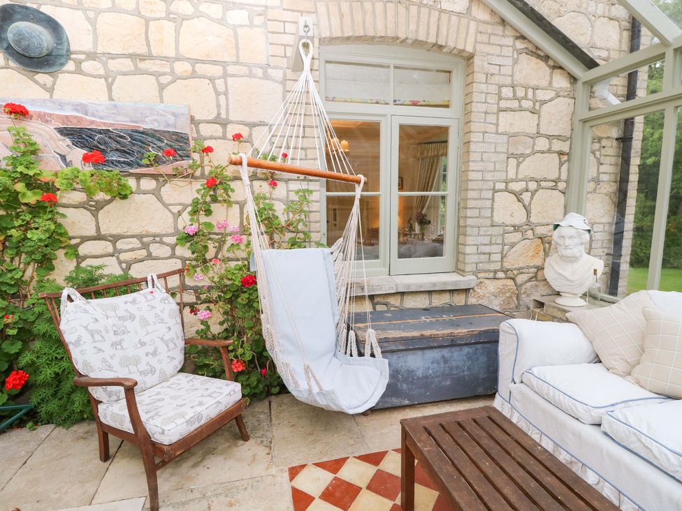 A conservatory with a hammock and armchair at Woodlands in Freshwater