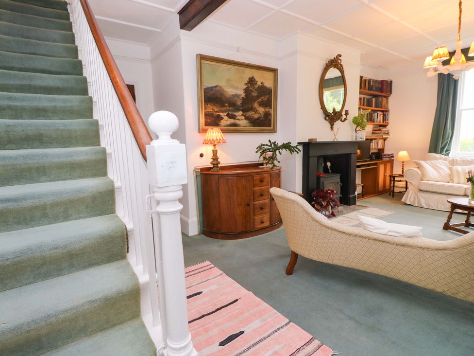 A living room with a staircase and various furniture pieces at Woodlands Freshwater