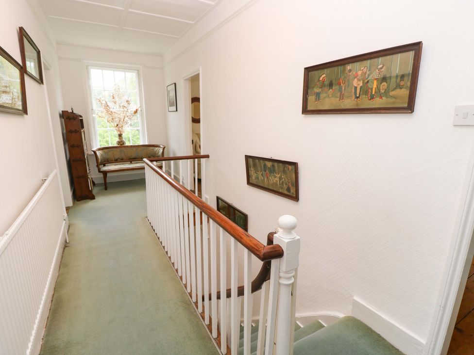 A hallway with a staircase and a sofa at Woodlands in Freshwater