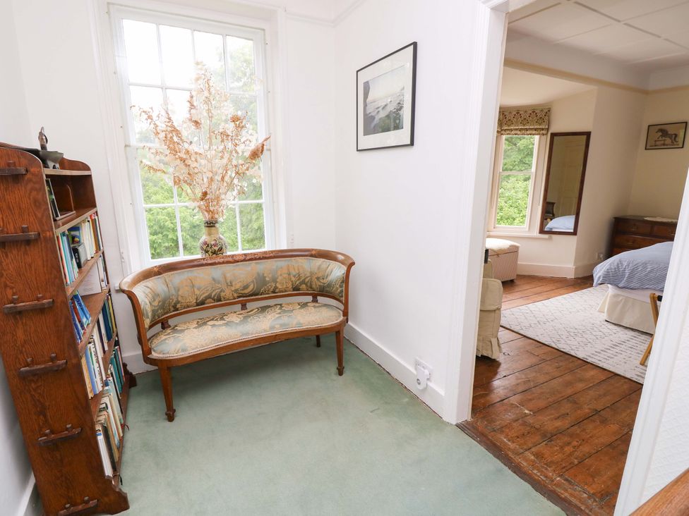 A hallway with a chair and bookshelf at Woodlands in Freshwater
