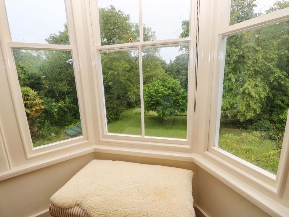 A sunroom with windows overlooking a garden at Woodlands Freshwater