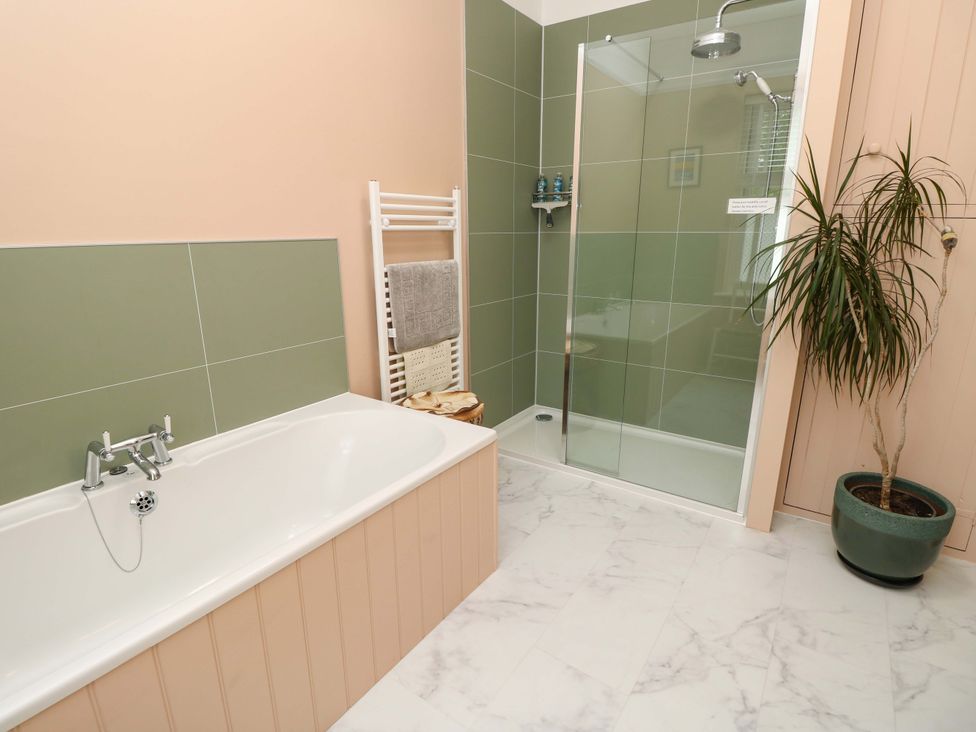 A bathroom with a bathtub and shower area at Woodlands in Freshwater