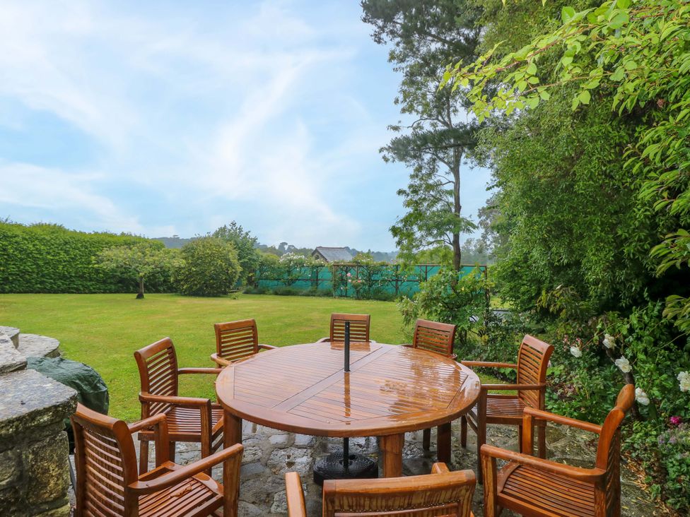 A garden with a wooden dining table and chairs at Woodlands in Freshwater