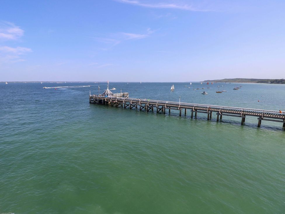 A pier extending into the water with boats in the background at Woodlands Freshwater