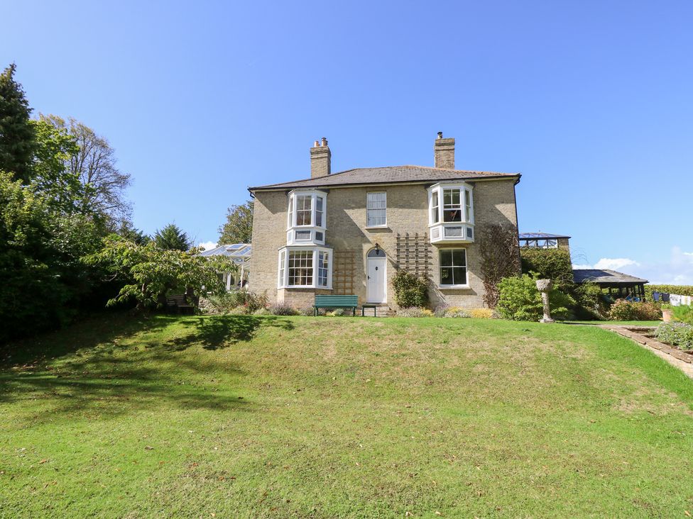 A two-story house with a lawn and trees at Woodlands in Freshwater