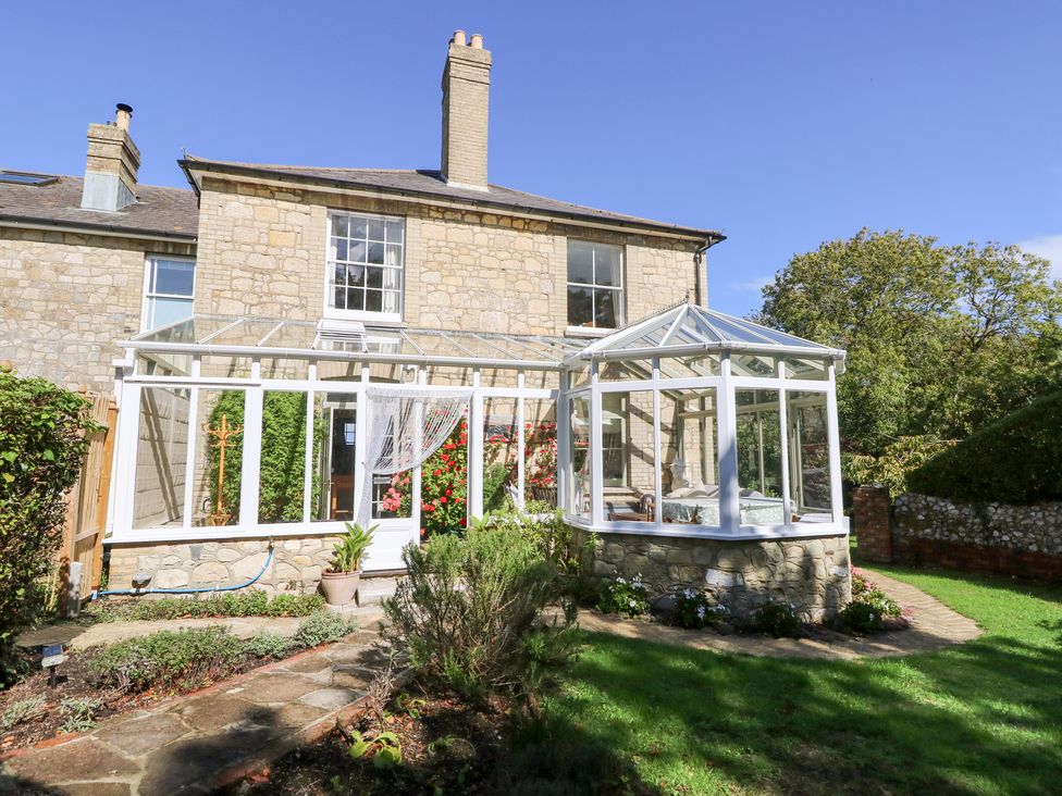 A conservatory with a garden and pathway at Woodlands in Freshwater