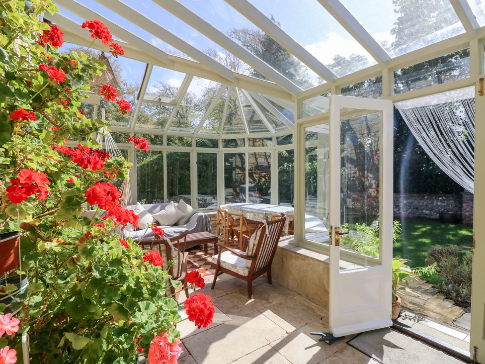 A conservatory with a sofa and table at Woodlands in Freshwater