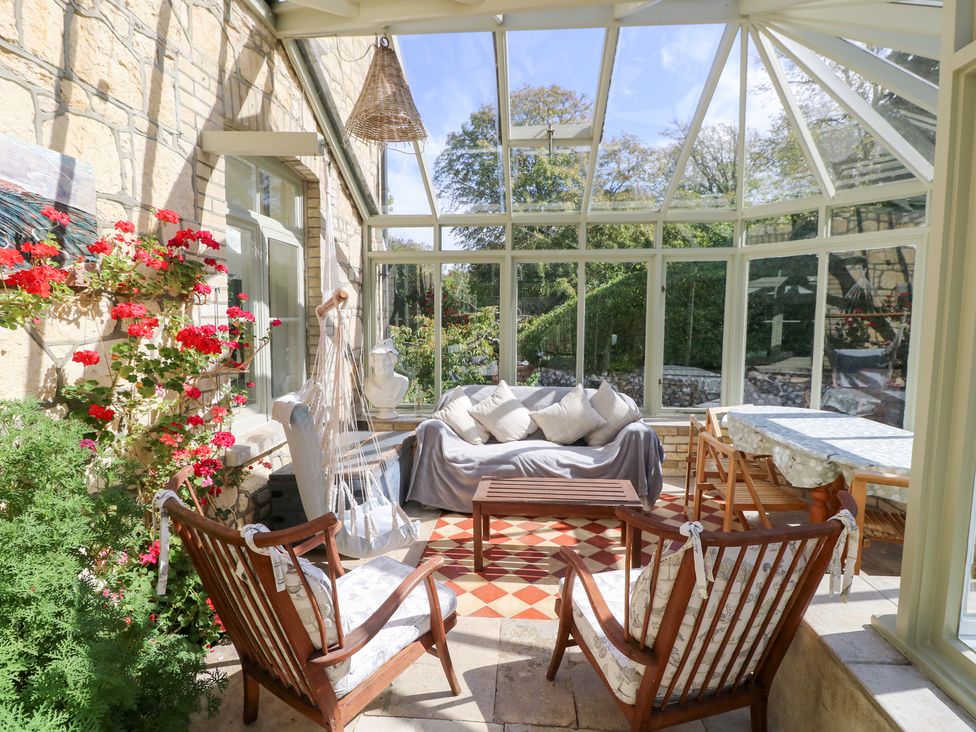 A conservatory with seating area and plants at Woodlands in Freshwater