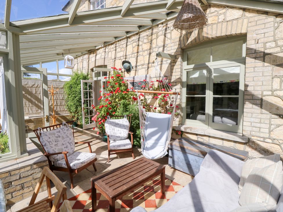 A conservatory with seating and flowers at Woodlands in Freshwater