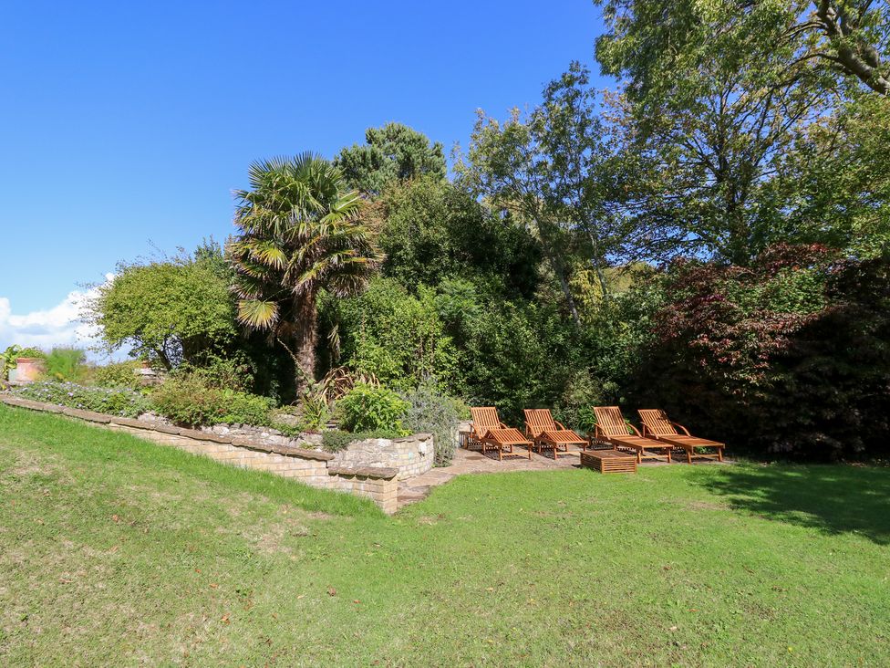 A garden with sun loungers and plants at Woodlands in Freshwater