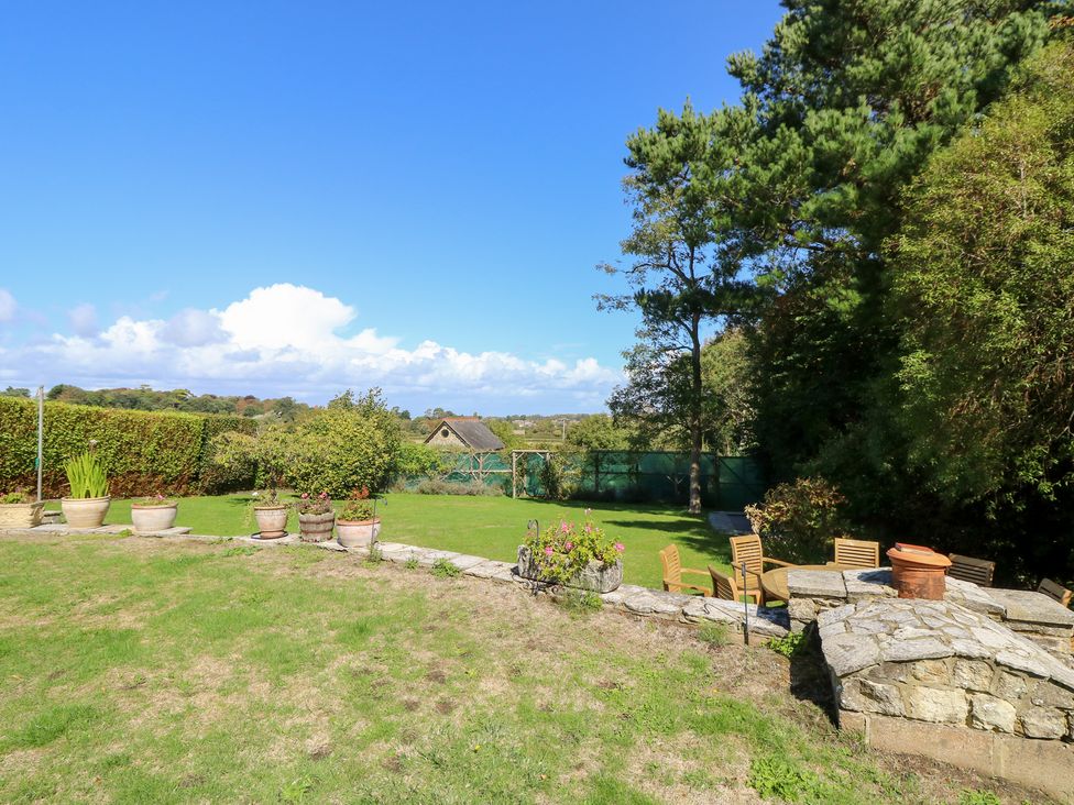 A garden with plants and a stone wall at Woodlands in Freshwater