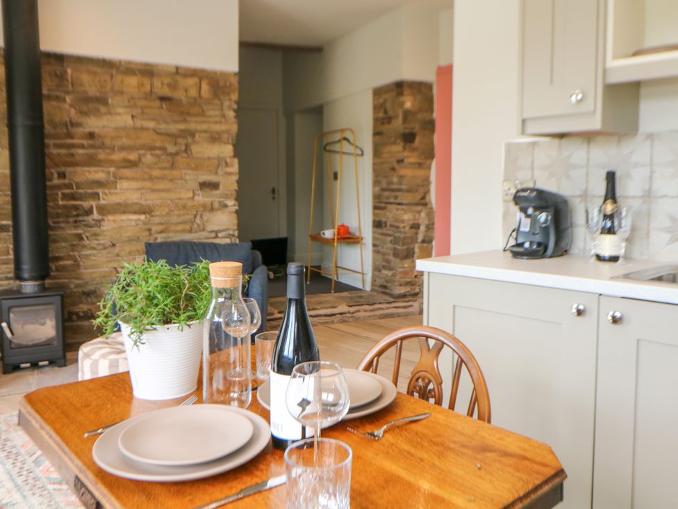 A dining room with a wooden table and kitchen features at The Plucking Shed in Stockport