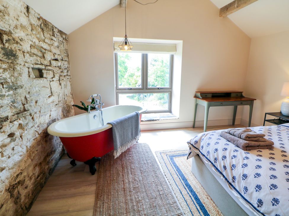 A bedroom with a bathtub and desk at The Plucking Shed in Stockport