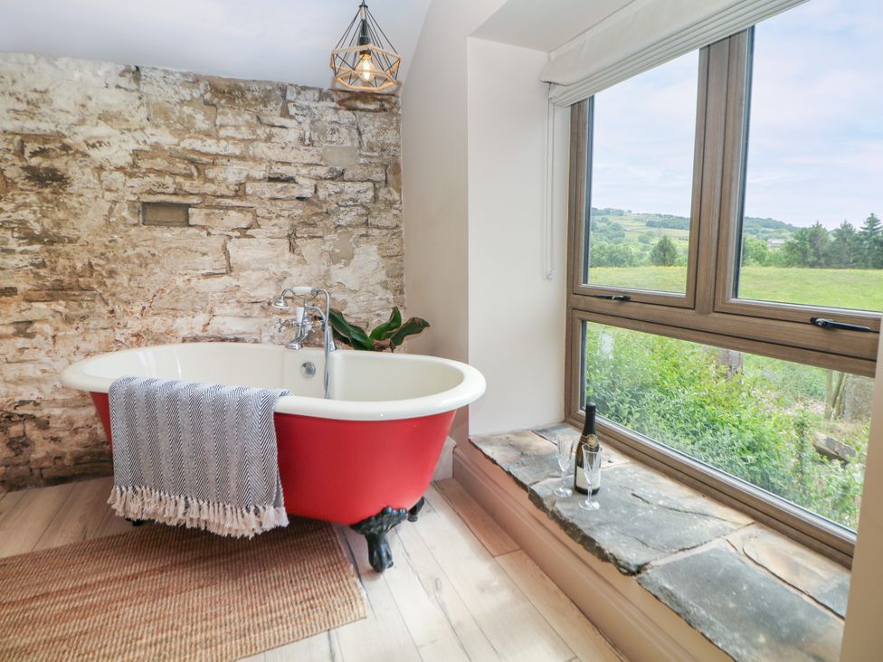 A bathroom with a red bathtub and a window at The Plucking Shed in Stockport