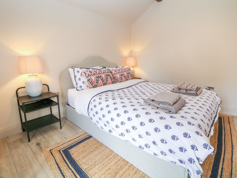 A bedroom with a bed and bedside table at The Plucking Shed in Stockport