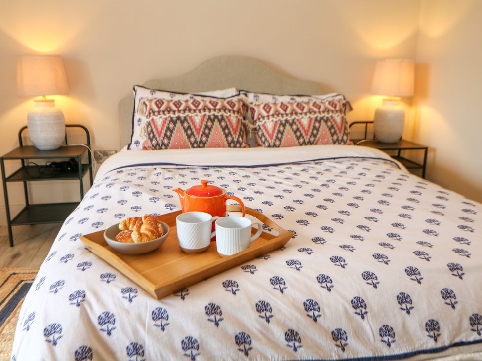 A bedroom with a bed and tray of pastries at The Plucking Shed in Stockport
