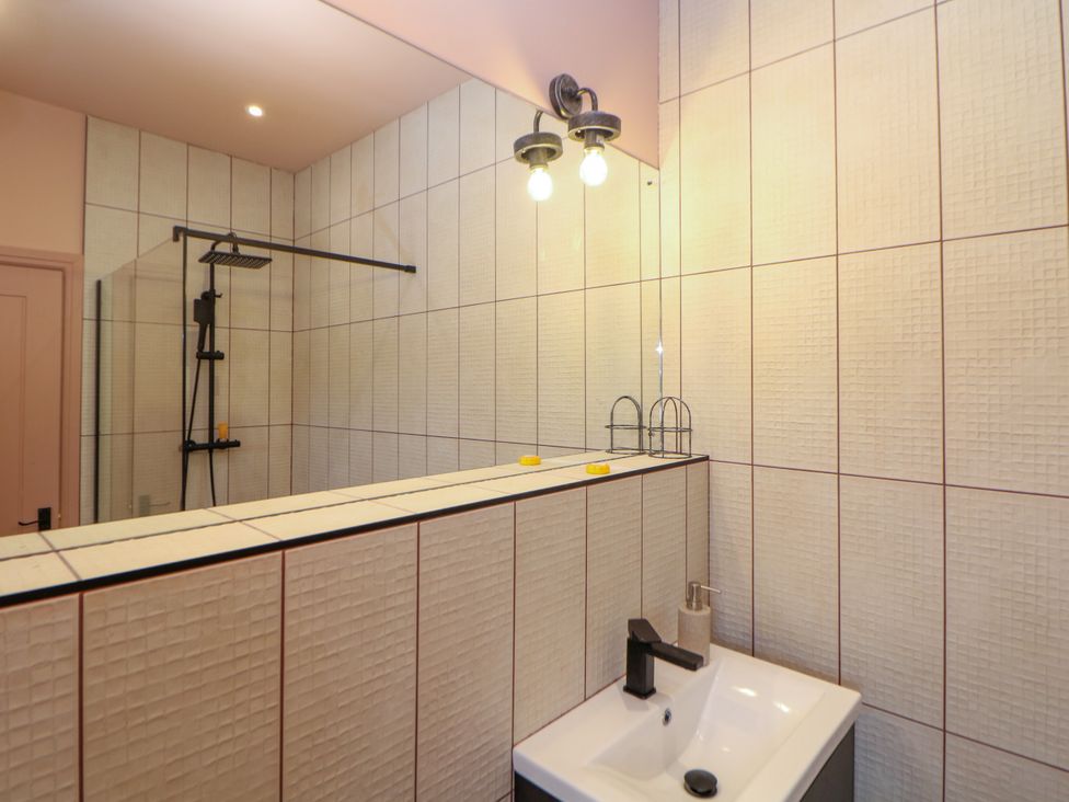 A bathroom with a wash basin and shower at The Plucking Shed in Stockport
