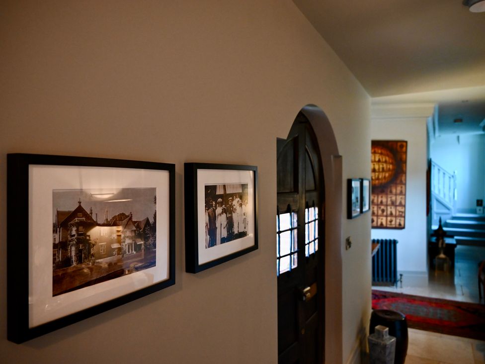 A hallway with framed photos and a staircase at Higginson House Marlow