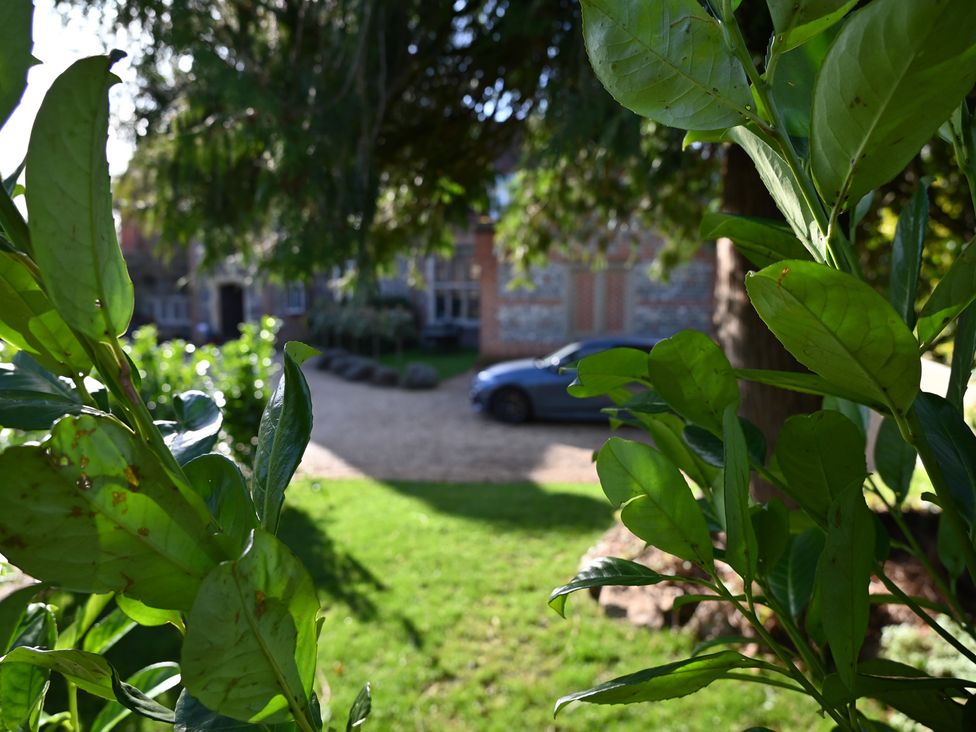 A view of a house and car through foliage at Higginson House in Marlow