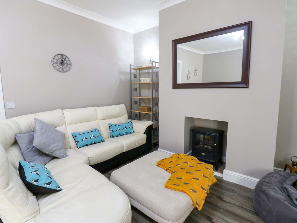 A living room with a sofa and shelf at Amblers Rest in Amble