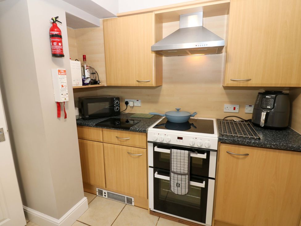 A kitchen with a stove, oven, microwave, and air fryer at Amblers Rest in Amble
