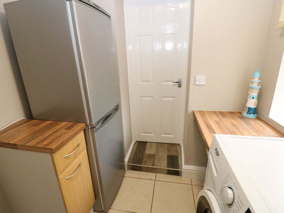 A kitchen with a refrigerator and washing machine at Amblers Rest in Amble