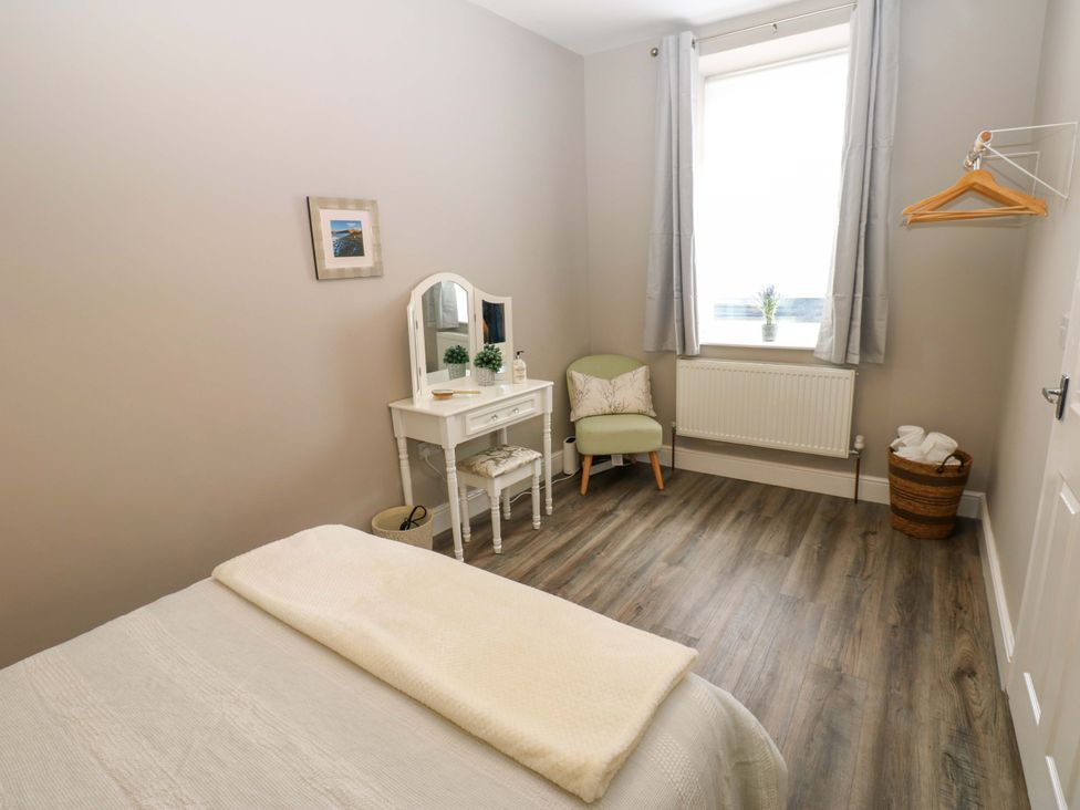 A bedroom with a bed and a dressing table at Amblers Rest in Amble