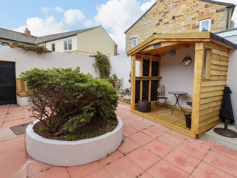 A garden with a wooden shed and a bush at Amblers Rest in Amble