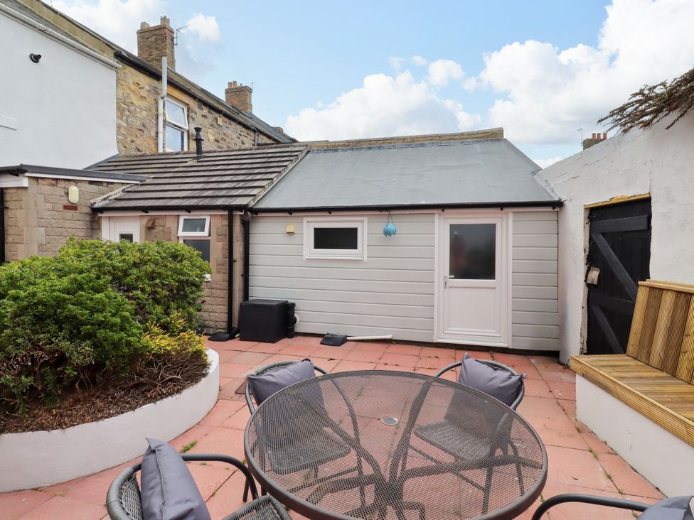An outdoor seating area with a table and chairs at Amblers Rest in Amble