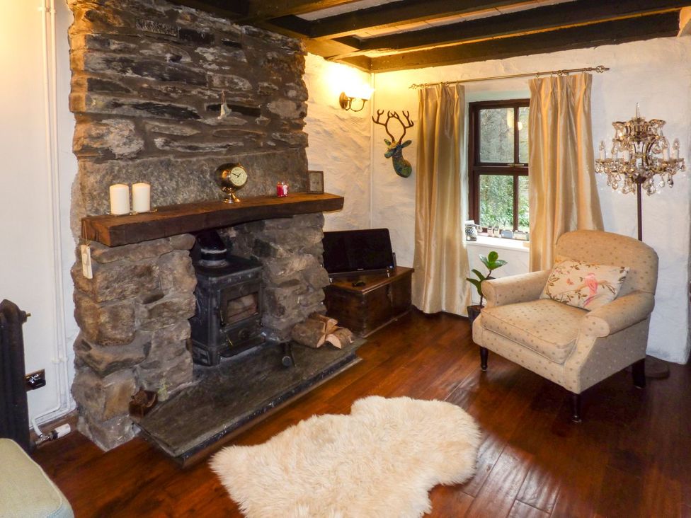A living room with a fireplace and sofa at Squirrel Cottage in Betws-Y-Coed