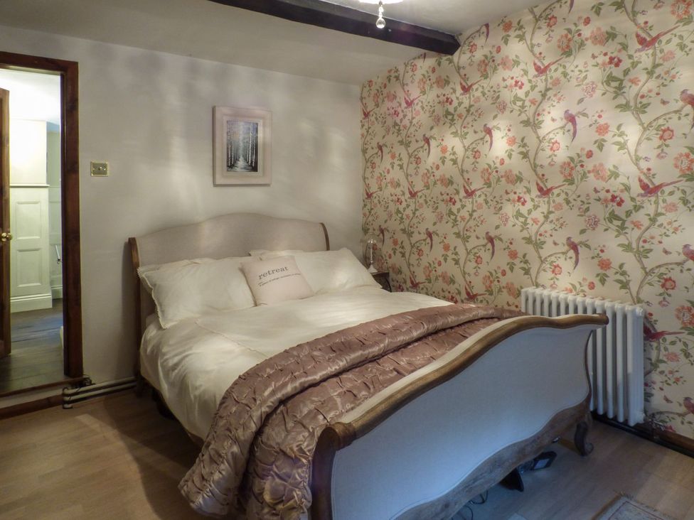 A bedroom with a bed and a painting at Squirrel Cottage in Betws-Y-Coed
