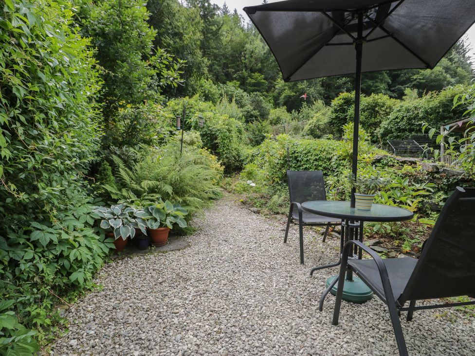 A garden with a gravel path and seating area at Squirrel Cottage Betws-Y-Coed
