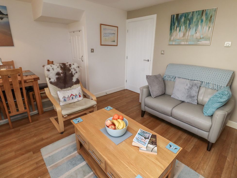 A living room with a sofa, armchair, coffee table, and dining area at Tidal Watch in Seahouses