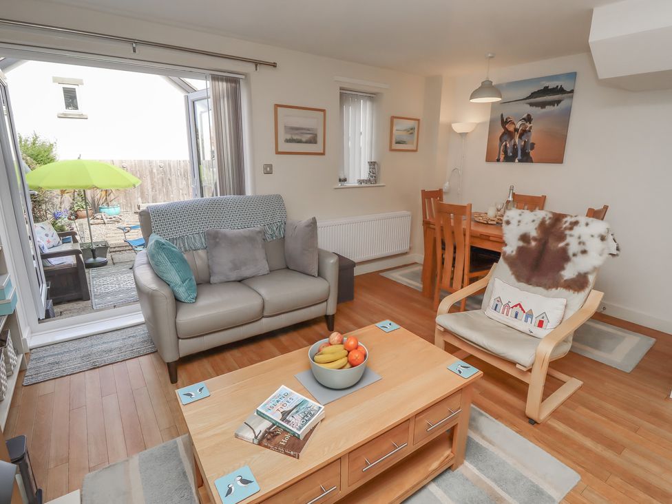 A living room with a sofa and dining area at Tidal Watch in Seahouses