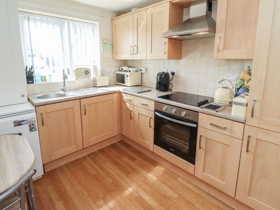 A kitchen with cabinets, stove, sink, and appliances at Tidal Watch, Seahouses