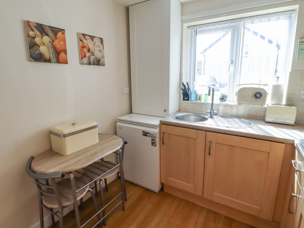 A kitchen with a table and fridge at Tidal Watch in Seahouses