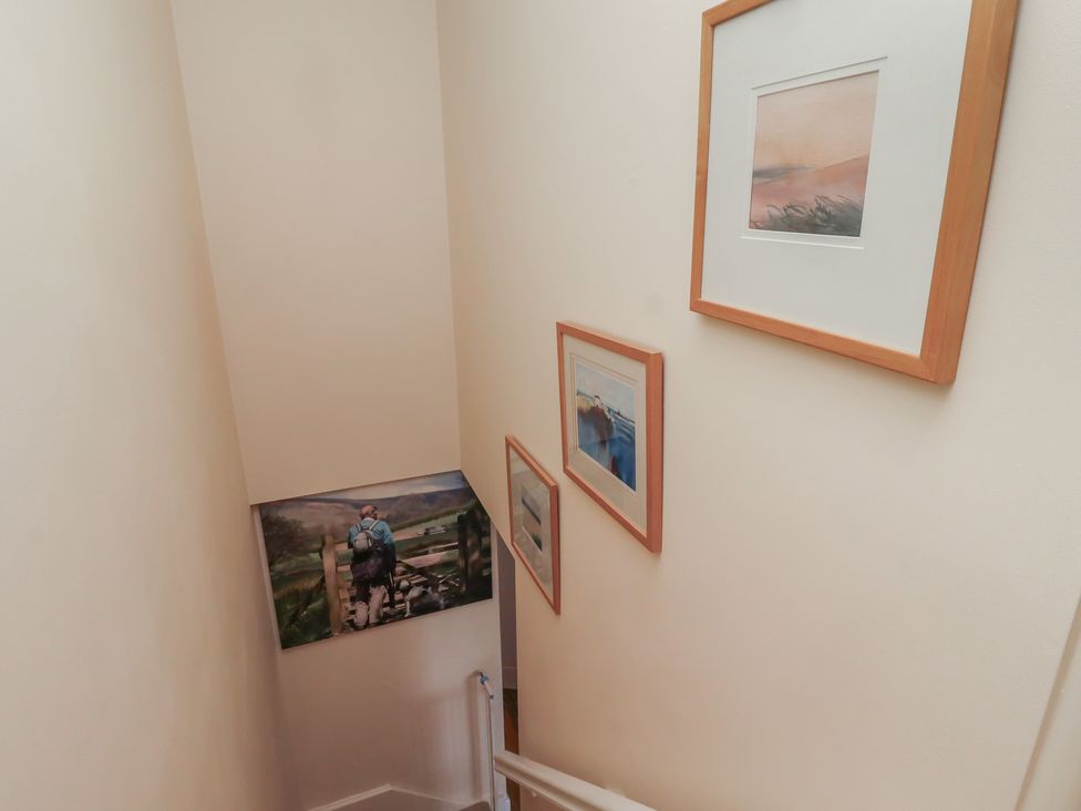 A staircase with paintings on the wall at Tidal Watch Seahouses