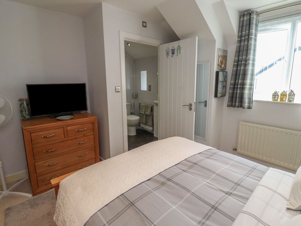 A bedroom with a bed and television at Tidal Watch in Seahouses