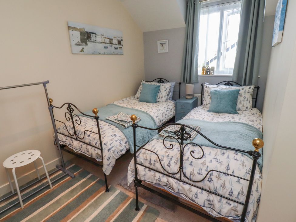 A bedroom with two beds and a bedside table at Tidal Watch in Seahouses