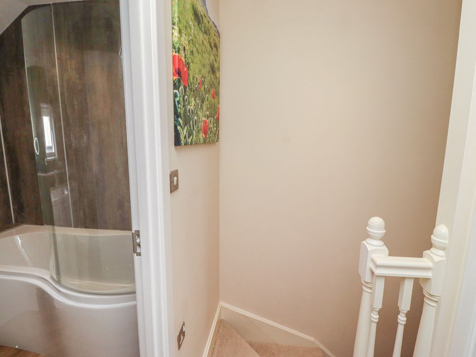 A bathroom with a bathtub and a staircase at Tidal Watch in Seahouses