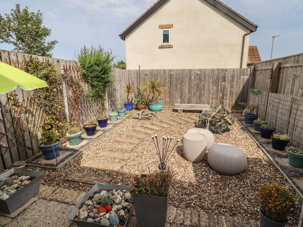 A garden with gravel path and potted plants at Tidal Watch in Seahouses